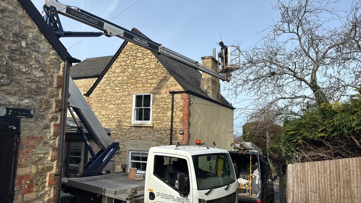Cherry picker reaching a rooftop chimney